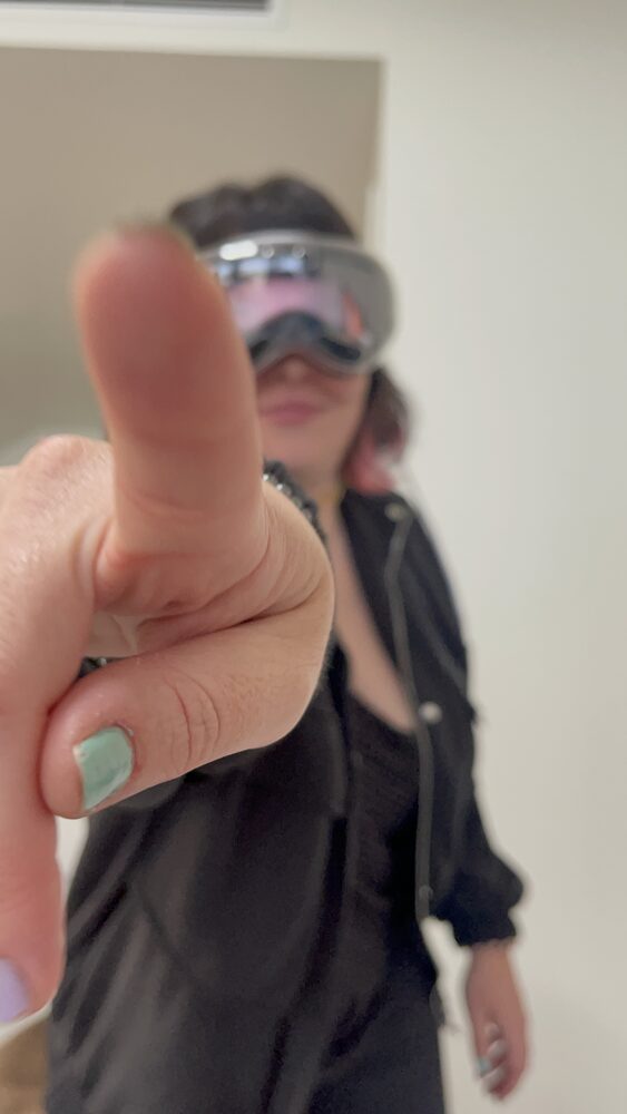 Celia wearing XR goggles, pointing playfully at the camera